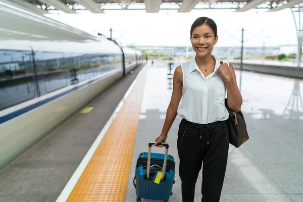 Asian businesswoman with carry-on hand luggage leaving train platform after transport. Morning commute to work or travel — Stock Photo, Image