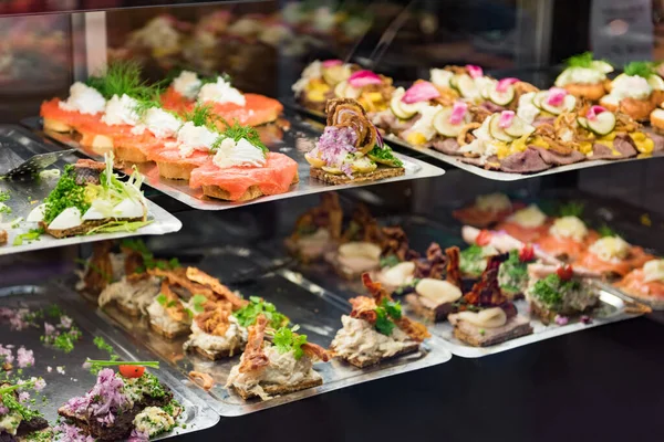 Danish smorrebrod traditional open sandwich at Copenhagen food market store. Many sandwiches on display with seafood and meat, smoked salmon. — Stock fotografie