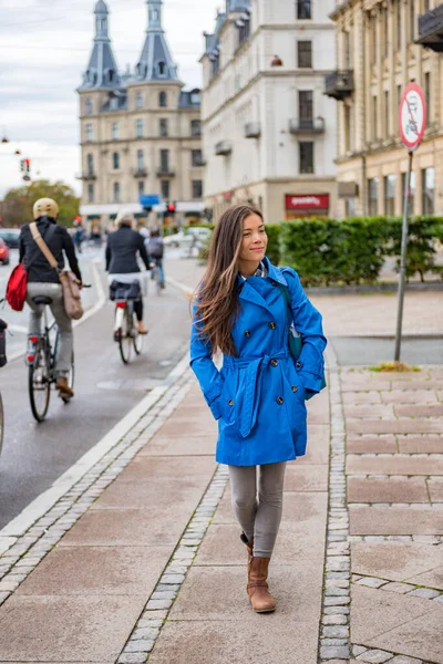 Asiatisk turist kvinna promenader i Köpenhamns stadsgata bredvid cykelvägen, modern pendla. Urban livsstil ung lycklig person pendla på hösten eller våren. — Stockfoto