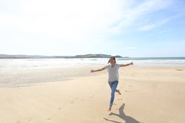 즐거운 자유의 여성은 해변 여행에서 팔을 벌린 채 마음대로 뛰놀고 있습니다. 여름 햇살 가득 한 휴양지 소녀. 인생의 행복 — 스톡 사진