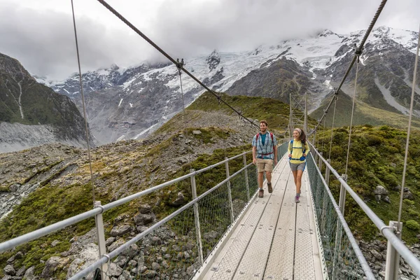 Szlak turystyczny Hooker Valley Track, Nowa Zelandia. Turyści przekraczający most na torze Hooker Valley, Aoraki, Park Narodowy Mt Cook ze śnieżnymi górskimi szczytami — Zdjęcie stockowe