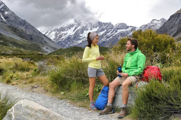 Caminhantes pessoas almoçando fazendo uma pausa durante a caminhada na montanha caminhadas aventura. Turistas relaxando na pista Hooker Valley em direção ao Monte Cook em viagens de verão na Nova Zelândia — Fotografia de Stock