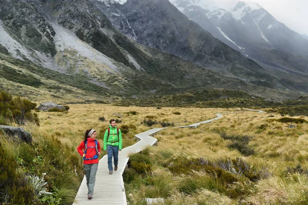 New Zealand trampers backpacking on Mount Cook Aoraki Hooker valley travel. hikers hiking walking on Hooker Valley Track in summer on boardwalk. Couple on travel holiday adventure — Stock fotografie