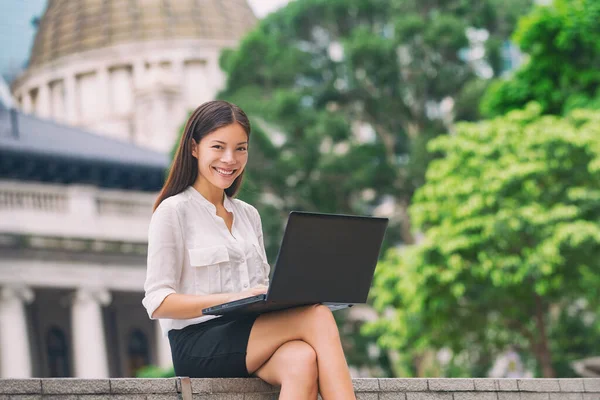 Geschäftsfrau mit Computer-Laptop arbeitet draußen und schaut auf den Bildschirm im Geschäftsviertel, Central, Hongkong. Junge Geschäftsfrau, die draußen sitzt. Asiatisch Chinesisch Kaukasische Frau — Stockfoto