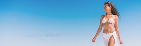 Luxury beach travel vacation woman relaxing banner walking on blue sky copy space background, lots of copyspace. Asian girl on tropical destination paradise wearing bikini swimwear — Stock fotografie