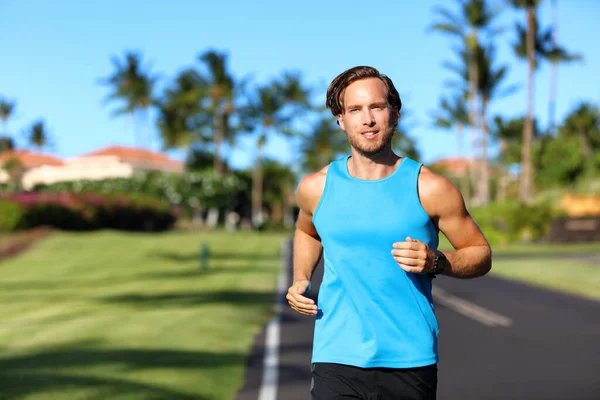 Running athlete man runner training cardio on road for marathon run. Athletic fit young sport fitness model outside in tropical summer city — Stockfoto