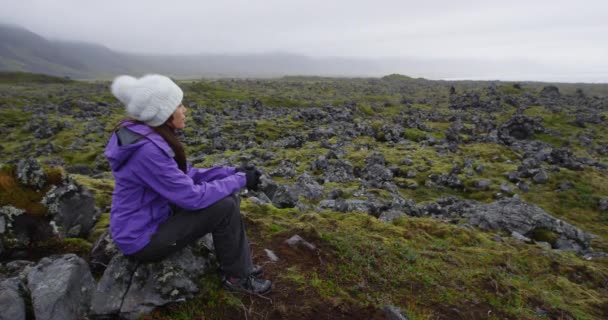 Mujer en caminata descansando en la roca de senderismo en Islandia - excursionista turístico disfrutando de la vista — Vídeos de Stock