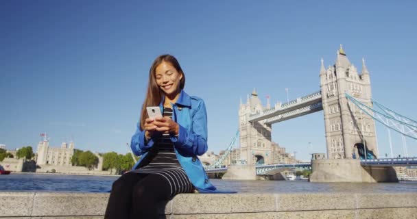 Teléfono - Mujer usando la aplicación de teléfono móvil por London Tower Bridge — Vídeos de Stock