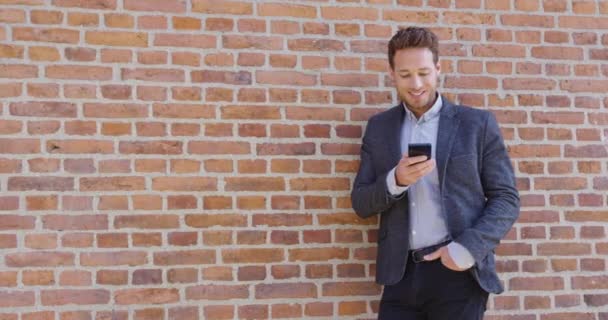 Бізнесмен смс-повідомлення додаток для телефону на вулиці міста на фоні цегляної стіни — стокове відео