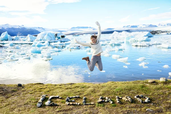 Islandia paisaje natural Laguna glaciar de Jokulsarlon. ISLANDIA texto escrito con piedras. Mujer saltando divirtiéndose visitando destino turístico hito atracción glaciar lago, el famoso Vatnajokull — Foto de Stock