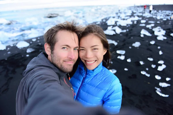 Adventure selfie by couple on travel on Iceland Diamond Beach. Woman and man tourist in amazing landscape Ice beach, Breidamerkursandur by jokulsarlon glacial lagoon glacier lake nature — Stock Fotó