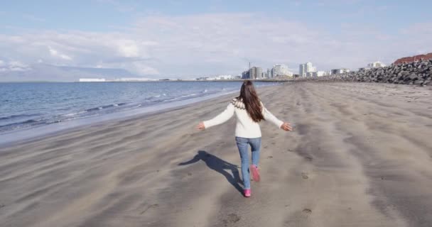 Islândia - Mulher em suéter islandês correndo na praia de areia preta em Reykjavik — Vídeo de Stock