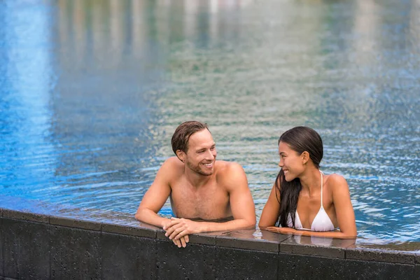 Lüks tatil beldesinde dinlenen havuz çifti tropik villa otelinde sonsuz havuzda yüzüyor. — Stok fotoğraf