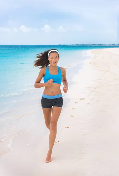 해변에서 운동복을 입고 달리는 여자. 좋아 하는 아시아인 여자 아이가 여름휴가 때 파란색 스포츠 브라와 반바지를 입고 조깅 훈련을 받는다. 여행하는 건강 한 생활 방식 — 스톡 사진