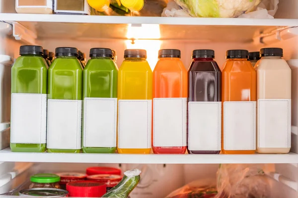 Juicing cold pressed vegetable juices for a detox cleanse diet. Dieting bydrinking organic fruits and vegetables juice made fresh and delivered in bottles at home in fridge — Stock fotografie