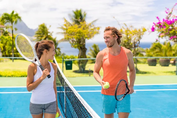 Тенісні гравці друзі весело сміються, граючи на відкритому корті. Пара або змішані подвійні тенісні партнери на вулиці влітку. Щаслива молодь, жінка і чоловік живуть здоровим активним спортивним способом життя — стокове фото