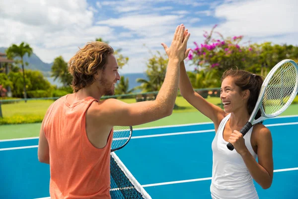 Fitness-Sport-Tennis-Paar gibt High Five energisch nach Spaß gemischtes Doppelspiel. Tennisspielerfreunde, die Spaß am Fitnesssport im Hotel haben, Sommerreiseurlaub. Asiatin, Kaukasier — Stockfoto