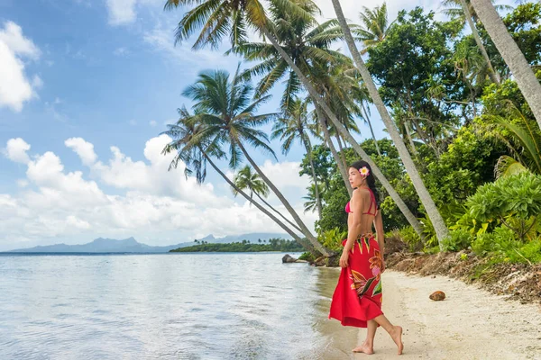 На Таїті жінка, що гуляє на пляжі, ходить у полінезійському костюмованому спідньому білизні на ідилічному райському острові у Французькій Полінезії. Червоний традиційний одяг, бікіні і квіткарка. — стокове фото