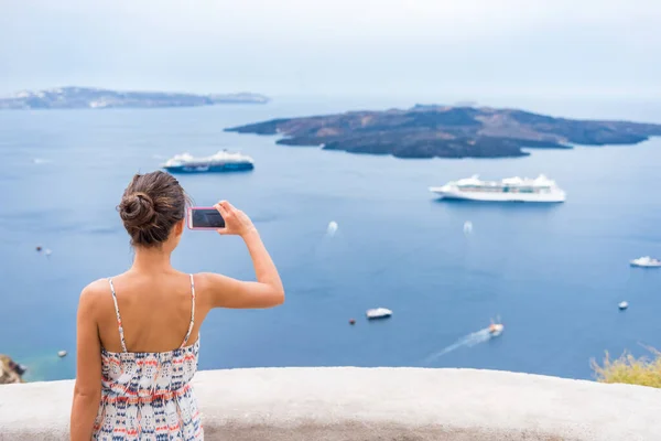 Europe cruise vacation summer travel tourist woman taking picture with phone of Mediterranean Sea in Santorini, Oia, Greece, with cruise ships sailing in ocean background — Stock Photo, Image