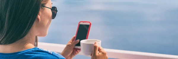 Teléfono mujer beber taza de café en Europa vacaciones de verano chica relajante en la cafetería lectura de teléfono celular en la terraza al aire libre vista del océano en Santorini, Grecia. Vacaciones de destino europeo. Panorama — Foto de Stock