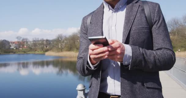 Telefon - Profesjonalny biznesmen korzystający ze smartfona spacerującego w parku — Wideo stockowe