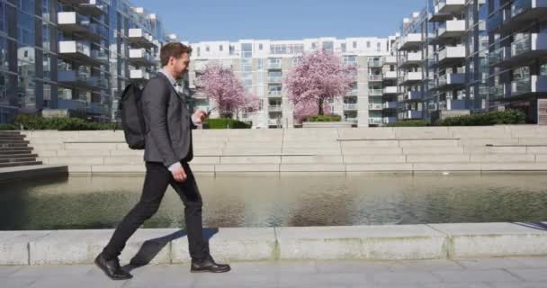 Hombre en el teléfono - joven hombre de negocios caminando con teléfono inteligente en traje casual inteligente — Vídeos de Stock