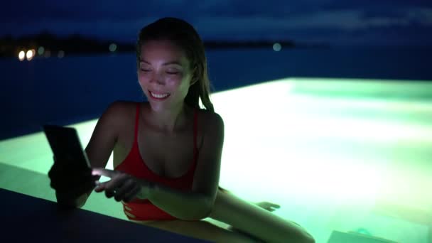 Teléfono: mujer que usa la aplicación de teléfono celular móvil de vacaciones en la piscina por la noche — Vídeo de stock