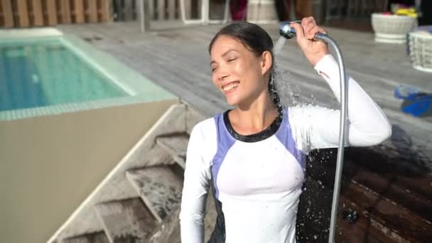 Woman in rashguard at luxury hotel outdoor showering washing hair and rinsing — Video