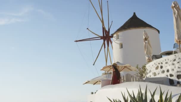 Turista de pie junto al molino de viento en Oia Santorini — Vídeo de stock