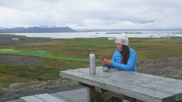 Woman outdoors using smart phone drinking coffee — стоковое видео