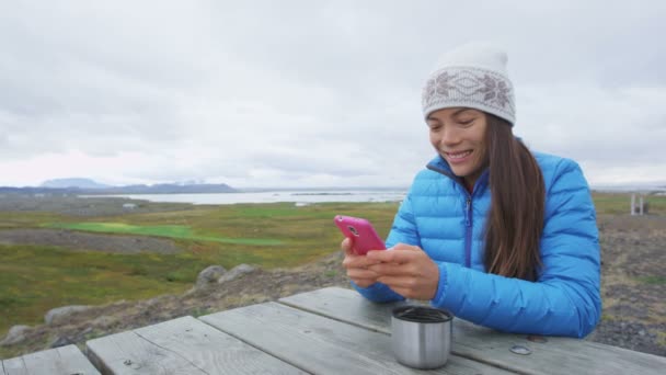 Woman outdoors using smart phone drinking coffee — стоковое видео