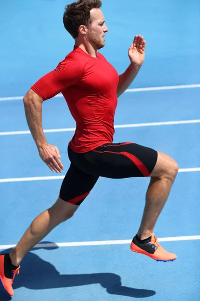 Corredor corriendo hacia el éxito en pista de atletismo. Concepto de logro de metas. Hombre atleta velocista haciendo un sprint rápido para la competencia en los carriles azules. Pista en marcha. — Foto de Stock