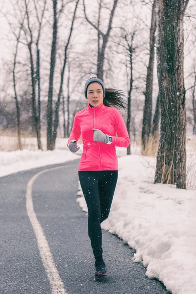 Wintersport Aziatische vrouw rennend in koude weer kleding. Chinese hardloper meisje training buiten. Atleet aan het joggen in het park tijdens de sneeuwstorm. Sport en fitness levensstijl. — Stockfoto