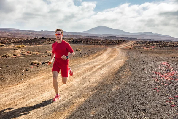 Trail biegnie sportowiec fitness człowiek biegnie na pustyni brud drogi w kompresji ubrania i nosić tech smartwatch do śledzenia cardio. Letni pejzaż. — Zdjęcie stockowe