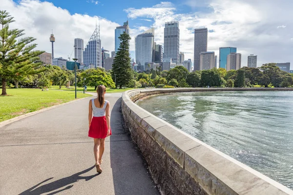 Sydney city girl turista a piedi nel parco urbano con grattacieli skyline sullo sfondo. Australia viaggi vacanza in estate. Stile di vita australiano. — Foto Stock