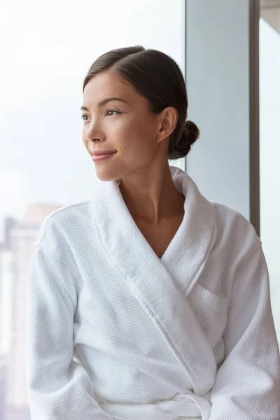 Donna asiatica che si rilassa al lussuoso centro benessere dell'hotel indossando accappatoio guardando il ritratto della finestra. Coccole stile di vita comfort al resort. — Foto Stock