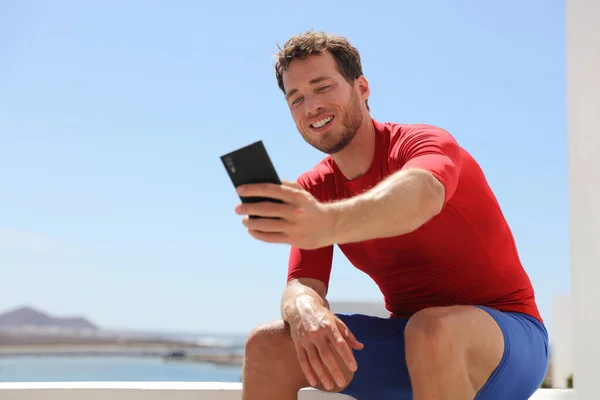 Fitness teléfono selfie entrenador físico hombre tomando fotos o grabación de vídeo vlog. Vlogging joven publicar en línea en el teléfono inteligente de redes sociales. — Foto de Stock