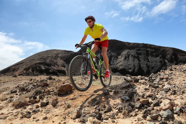 Mountain bike MTB biking man racing in mountain desert trail rocks path jumping in the air riding bicycle in mountains. Professional bicycle rider training outdoors. Sports and fitness. — Stock Photo, Image