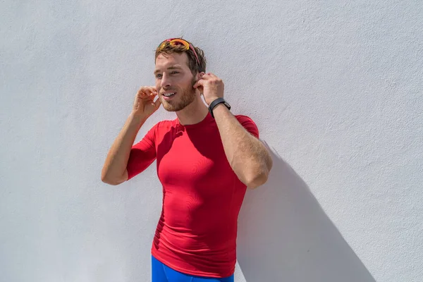 Homem atleta corredor se preparando para o treino colocando fones de ouvido sem fio bluetooth para ouvir música no smartphone durante o exercício de corrida. — Fotografia de Stock