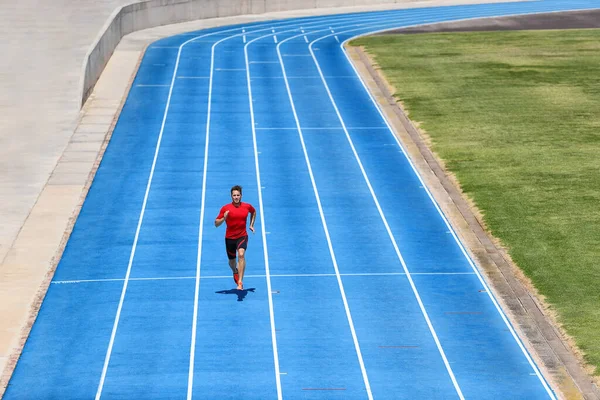 Sprinter biegacz sportowiec biegnie po torze zewnętrznym i bieżni pasy na stadionie. Sport i zdrowie aktywny trening na niebieskich torach. — Zdjęcie stockowe