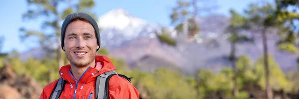 Escursionista uomo escursioni nella foresta paesaggio banner montagna. Buon sano giovane sportivo in forma con zaino, giacca e cappello trekking nella natura durante la primavera all'aperto. Montagne sfondo. — Foto Stock