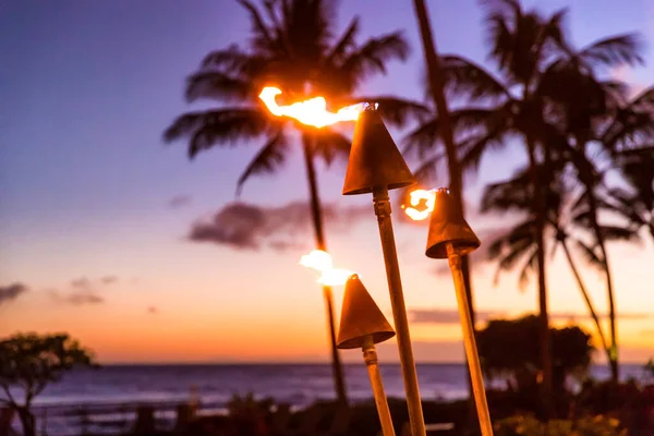 Puesta de sol de Hawai con antorchas de fuego. Icono hawaiano, luces ardiendo al atardecer en el resort de playa o restaurantes para iluminación y decoración al aire libre, ambiente acogedor. — Foto de Stock