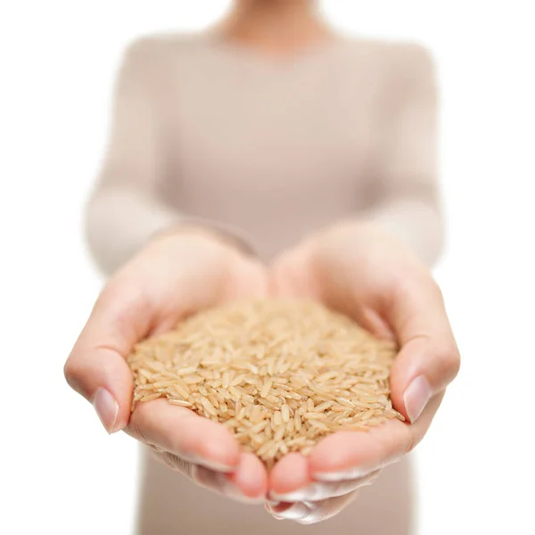 Grãos de arroz integral comida natural closeup em mãos abertas. Mulher mostrando grão de arroz cru não cozido no estúdio — Fotografia de Stock