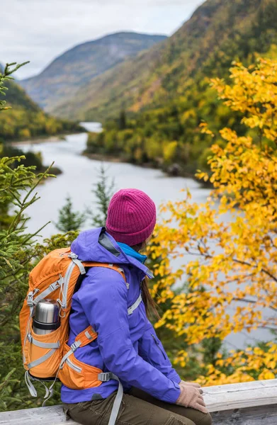 秋の紅葉の山の風景の景色を見て女性ハイカーのハイキング。秋の自然ハイキング中に川の近くでリラックスして立つ冒険旅行. — ストック写真