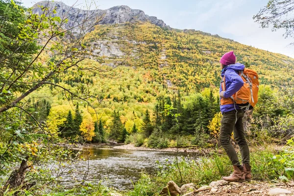 秋の紅葉の山の風景の景色を見て女性ハイカーのハイキング。秋の自然ハイキング中に川の近くでリラックスして立つ冒険旅行. — ストック写真