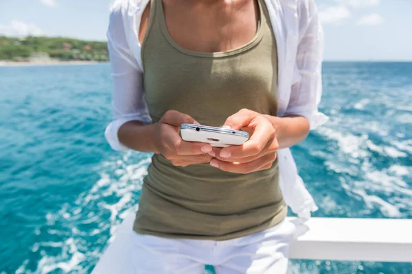 Tourist using smartphone mobile app to text sms while traveling on cruise ship tour. Woman holding phone texting on boat ride during travel summer vacation. —  Fotos de Stock
