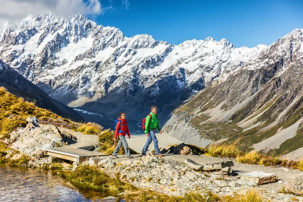マウントクックトレイルの新しいニュージーランドの旅行ハイカーは、ミューラー・ハットにハイキングをします。雪を背景に山のキャップとアルプスのルートを歩いてトランプライフスタイルのカップルの観光客 — ストック写真