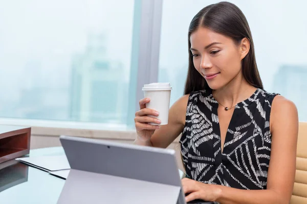 Πορτρέτο μιας σοβαρής επιχειρηματία χρησιμοποιώντας φορητό υπολογιστή στο γραφείο, ενώ πίνοντας ένα φλιτζάνι καφέ. Ασιάτισσα που εργάζεται στον υπολογιστή στο σπίτι — Φωτογραφία Αρχείου