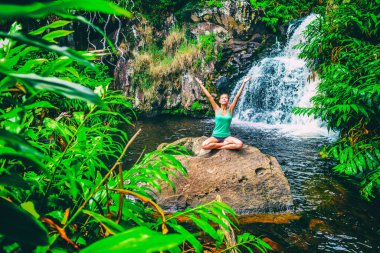 Yoga nature wellness meditation retreat woman at tropical waterfall forest in Kauai, Hawaii. Happy girl with open arms in serenity enjoying lush outdoors, mindfulness concept clipart