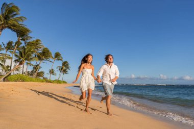 Happy couple relaxing running together on beach. Young multiracial people having fun during sunset on tropical vacation. Summer travel destination clipart